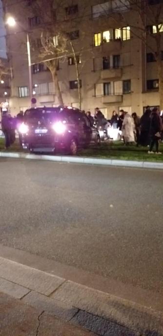 Une photo prise le soir montre une voiture arrêtée en travers des voies du tramway, situées sur le terre-plein végétalisé. Des personnes essaient de pousser le véhicule.