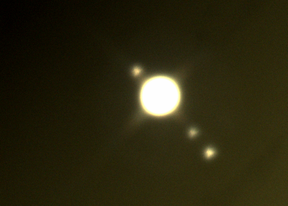 Aufnahme von Jupiter und drei inneren Monden durch ein Teleskop.