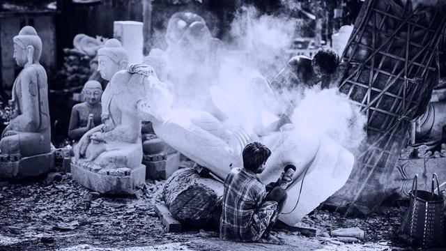 Two craftspeople making a Buddha statue.