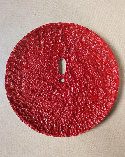 Carved wooden plate with random texture and an exclamation sign cut out in the middle painted in red. 

