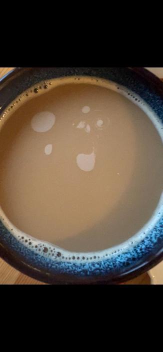 Top down shot of a mug of milk coffee, the foam swirling around forming galaxy-like shapes