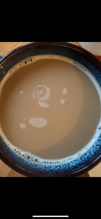 Top down shot of a mug of milk coffee, the foam swirling around forming galaxy-like shapes