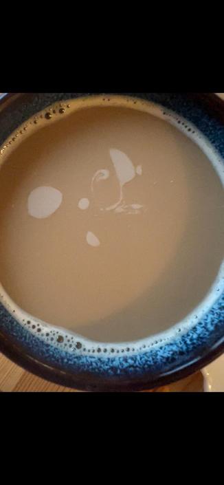 Top down shot of a mug of milk coffee, the foam swirling around forming galaxy-like shapes