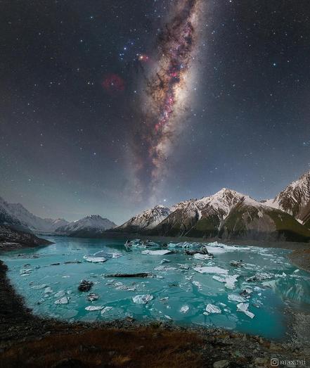 The milky way core, rising above New Zealand's Tasman Lake. The scene is illuminated by the light of the crescent moon, revealing details and colours in the icebergs below.