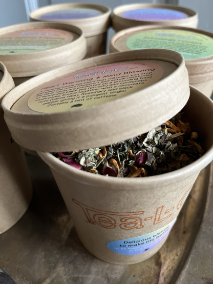 a brown paper cup with a peek under the lid which shows beautiful colourd loose leaf herbs