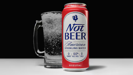 A tall can of Not Beer with its white label on red background with a rooster logo at the top. Behind it is a glass mug featuring the sparkling water. The can's aesthetic is reminiscent of a Budweiser can with a hint of Pabst Blue Ribbon.

People ages 18 to 34 are binge-drinking alcohol less often. About 40% in that age bracket don’t drink at all. 

While it sounds like an alternative for sober drinkers, Dandurand’s Marketing doesn’t only play to a non-drinking audience.

“Say you had three drinks and you’re like, ‘Alright, I want to kind of take my foot off the gas a little bit.’ Perfect occasion for a Not Beer,” he said.
He also calls it a “healthy substitute for alcohol” and an alternative to “boring sparkling water brands.” 

Not Beer is a zero calorie sparkling water created by Dallas man Dillon Dandurand. His parents are entrepreneurs, too: They created the men's skincare line Jack Black. (Not Beer)