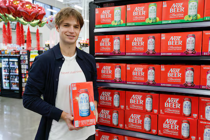 Dillon Dandurand holding a red case of his Not Beer in a store in front of a shelf display of cases of Not Beer.

Dallas entrepreneur Dillon Dandurand said he created Not Beer for those who want to drink with friends and have a good time, without the buzz or hangover. "No drunk texts," the founder jokes.(Elias Valverde II / Staff Photographer)