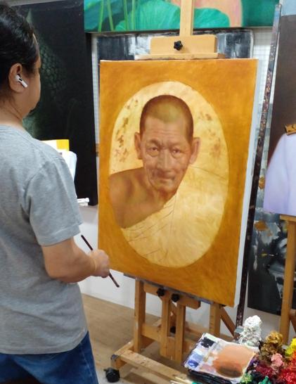 a photo of Geng painting a portrait of a monk, the monk is done with amber and gold tones, very realistic , the artist is seen from the back holding a brush in a three quarter view 