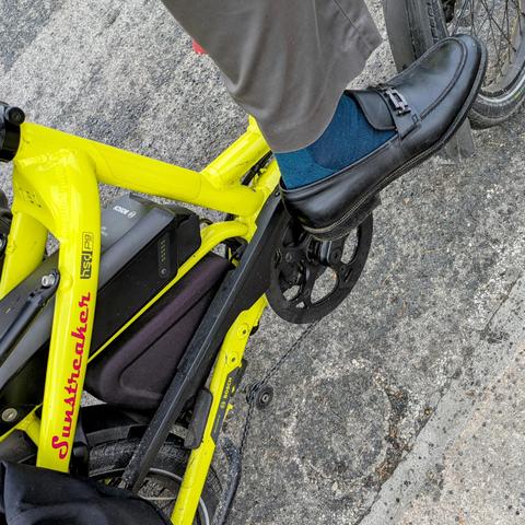 A  photo of my right foot on the pedal of a 

yellow Tern HSD cargo bike with its name, Sunstreaker, in red on the seat stay

I'm wearing

Black loafers and teal socks under a slate grey pantleg