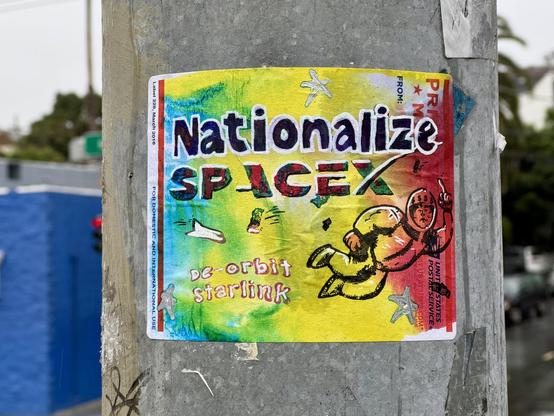 A colorful sticker affixed to a dark gray metal surface. The sticker is predominantly yellow and orange, with streaks of green and blue. It features the text "Nationalize SpaceX" in large, stylized letters. Below this, smaller text reads "De-orbit starlink." A cartoon drawing of Elon Musk in a spacesuit floats to the right. The metal surface below the sticker has additional white graffiti that reads "MASTERY" and other illegible markings.  This art was printed on an a USPS priority mail label using colorful inks, a Risograph printer, white out ink, and sharpie.