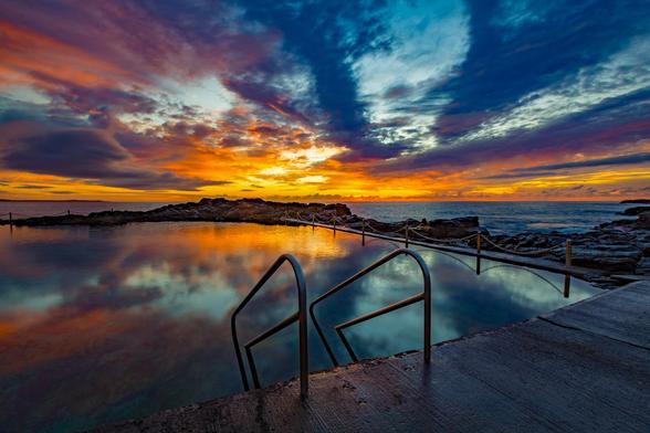 Blowhole Point Ocean Pool is located in Kiama in South Coast NSW Australia. This photograph was taken at sunrise, looking out over the Pacific Ocean as a beautiful sky coloured up and reflected in the calm pool water.
