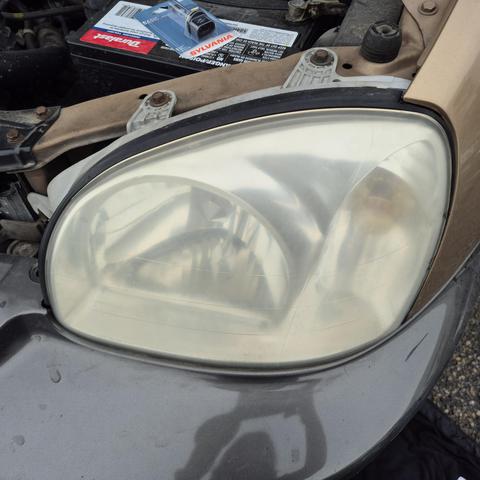 A miserable close up "before" photo of a very cloudy and dirty Hyundai Santa Fe headlight plastic covering.