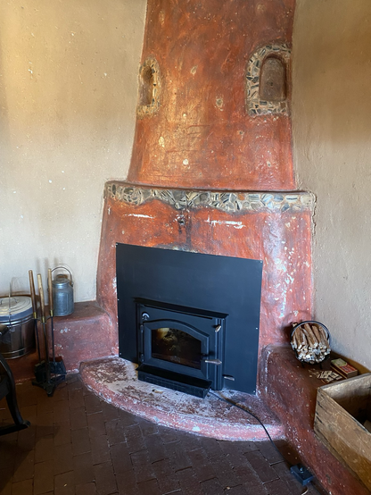 Black woodstove insert in a kiva style hearth 