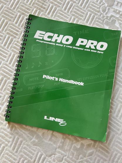 A manual for a Line 6 Echo Pro. The cover is green. It is on a nondescriupt fabric background. 