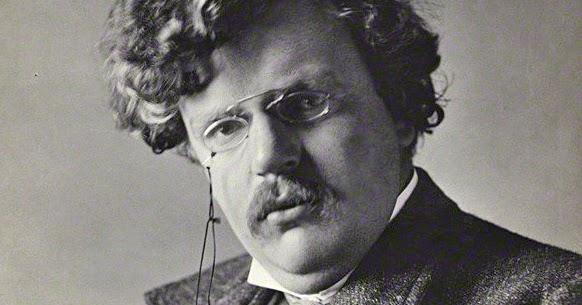 A black and white photo portrait of G.K. Chesterton. He is gazing into the camera at a slightly angles position. He has a full head of wavy hair, a bushy mustache, and is wearing pince nez eyeglasses.