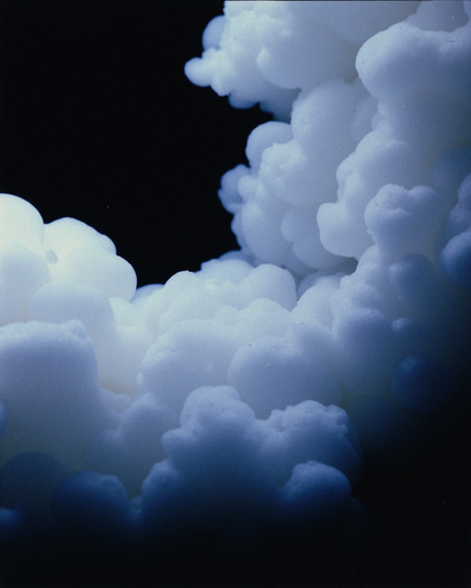 A cloud-like formation of soft, rounded shapes in a deep blue hue against a dark background. The image evokes a sense of weightlessness and tranquility