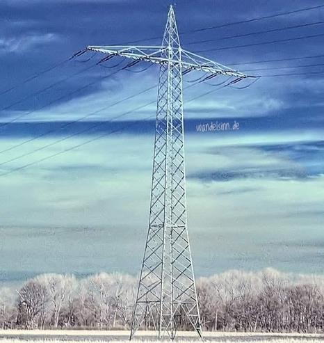 Ein Strommast in einer verschneiten Landschaft mit fast weißen Bäumen. Blauweißer Himmel. In einer blauen Schliere der Wolken der Schriftzug: wandelsinn.de