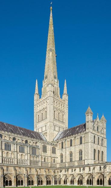 a photo of a large building, a church , a massive tower with very tall spire, the building is so big, it was one of the largest ones in england when it was built, it is light tan colored with purple-brown roof , there is a big tower and then a huge complex around it 