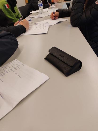Les mains de jeunes lycéens en train d'écrire, attablés. On distingue des lignes d'écriture manuscrites sur les feuilles blanches.
