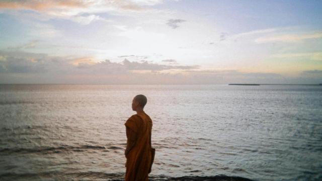 Buddhist monastic with ocean in background.