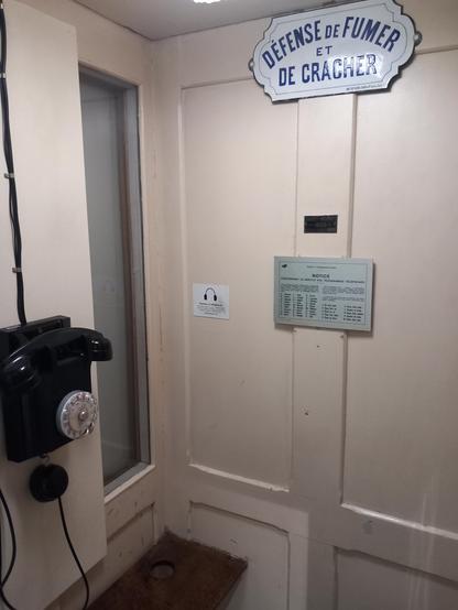Au musée de la Poste, une cabine téléphonique ancienne est reconstituée. Une plaque indique : "Défense de fumer et de cracher."