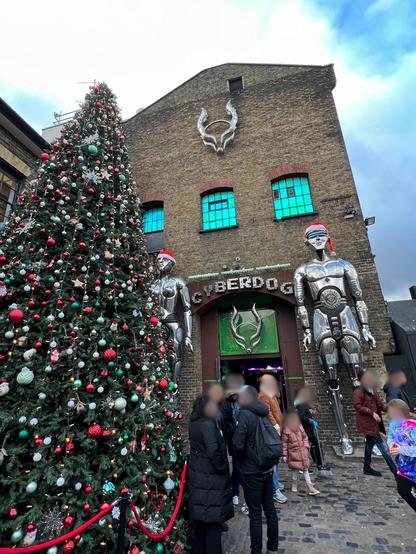 Entrée iconique de Cyberdog : L'entrée de Cyberdog avec ses statues futuristes et un sapin de Noël à Camden Market. The entrance of Cyberdog with its futuristic statues and a Christmas tree at Camden Market. L'ingresso di Cyberdog con le sue statue futuristiche e un albero di Natale al Camden Market.