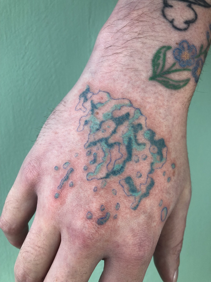 Tatouge d’une vague turquoise, fait au handpoke sur une main