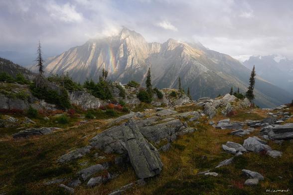 Soft light drapes over the mountains, their sharp ridges brushed with mist. A faint rainbow flickers against the rock face, vanishing and reappearing as the clouds shift. The alpine terrain, scattered with weathered stone and pockets of evergreens, feels caught between seasons—warm tones of autumn blending into the cool hush of approaching dusk. A moment on the edge of change, held in quiet suspension."

'Rise to Action' (2023)