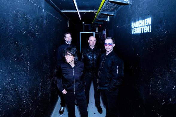 Die Band VonLiebknecht. Drei Männer, eine Frau. Alle schwarz gekleidet. Sie stehen in einem engen, schwarz gestrichenen Gang. An einer Wand steht "Rauchen verboten!". Das Foto wurde von Christian Schuller aufgenommen.
