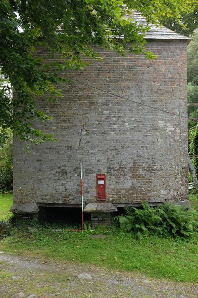 A square building with conical roof and a postbox set into the wall. It sits on 8 brick supports.
