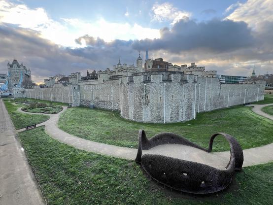 Vue sur la Tour de Londres : Les remparts historiques de la Tour de Londres sous un ciel nuageux. The historic walls of the Tower of London under a cloudy sky. Le mura storiche della Torre di Londra sotto un cielo nuvoloso.