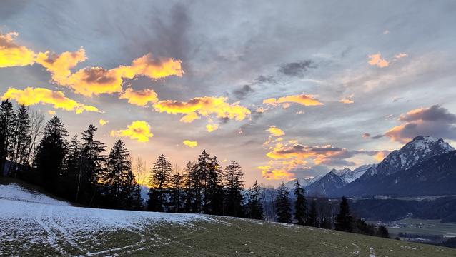 Beautiful sunset with orangish-yellowish clouds and snowy mountains.