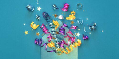 An open envelope with colorful curling ribbons and star-shaped confetti spilling out against a blue background.