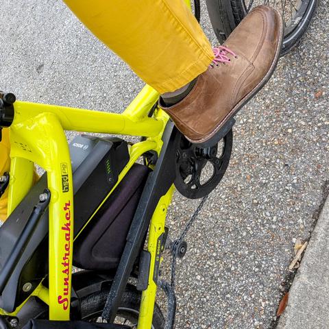A photo of my right foot on the pedal of a 

yellow Tern HSD cargo bike with its name, Sunstreaker, in red on the seat stay

I'm wearing

brown moc-toe boots with pink laces under a yellow pantleg