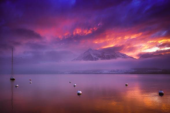Niesen und Thunersee im Abendlicht mit Nebel und roten Wolken. 