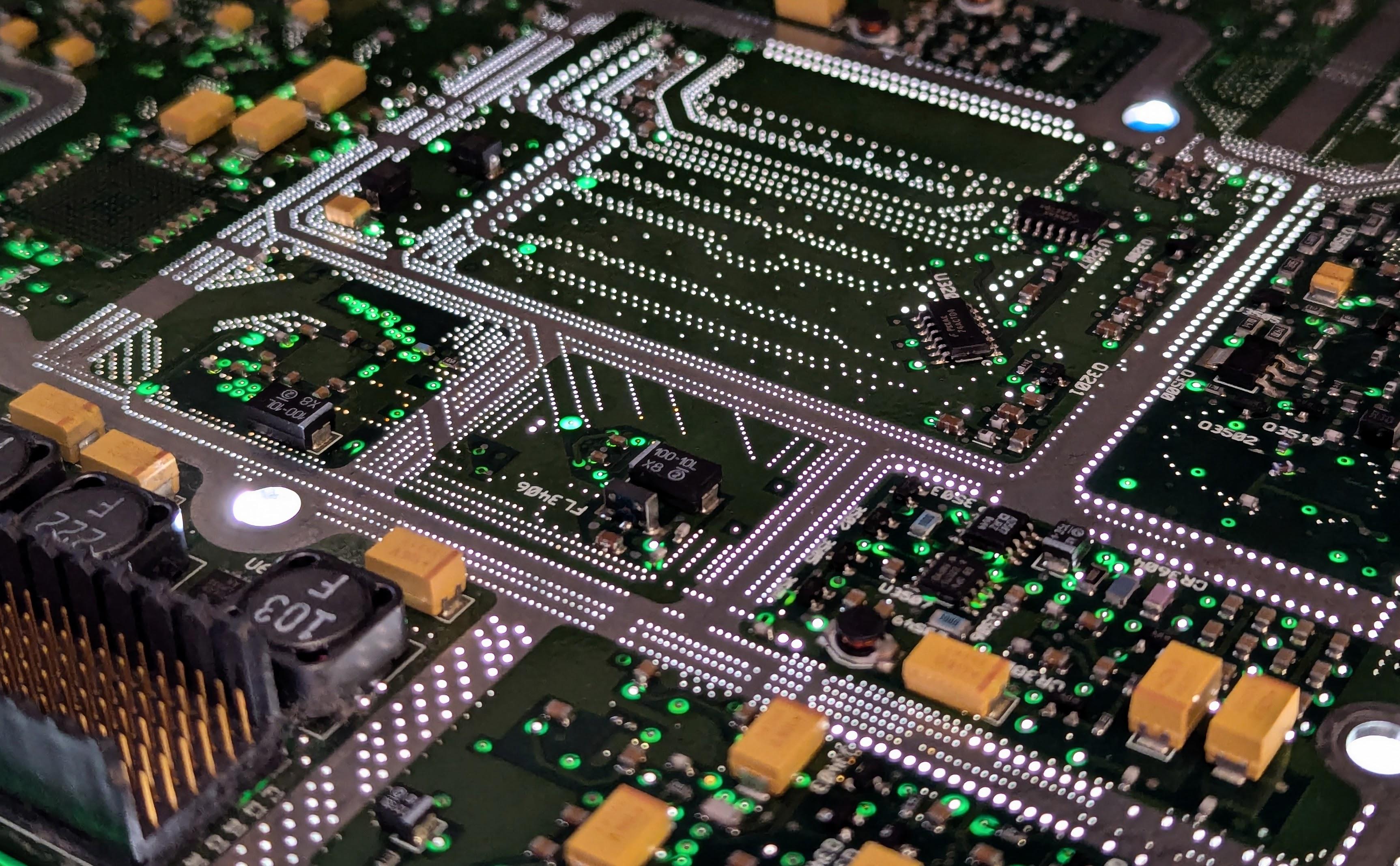 A large PCB lit from underneath, highlighting many tiny via holes following the edges of internal strip-line traces