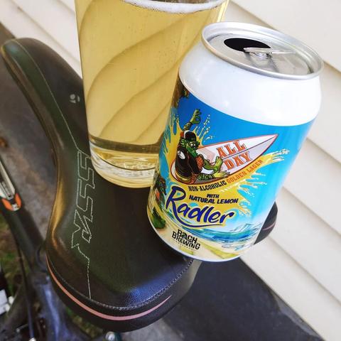 A beer can and glass of non-alcoholic beer balanced on a bicycle saddle.