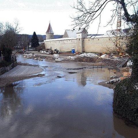 | Les eaux de la Sulz se gonflent au pied des fortifications du parc du Bourgmestre de Berching. Des pierres ont encore été emportées. Mais ce n’est pas encore une inondation, c’est deux jours de pluie. La petite île du bas a disparu. La passerelle commence à bouger, les broussailles et les débris commencent à s’accumuler. Du jour au lendemain, l’eau est montée jusqu’aux murailles. Arrêt des travaux. Les palissades contre le rivage sont détruites. La Sulz se dirige désormais presque verticalement vers les murs médiévaux de la ville.