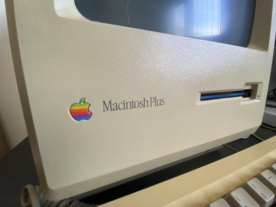 Close up of the logo on the front of the case of a Macintosh Plus, with the infamous Apple rainbow logo.