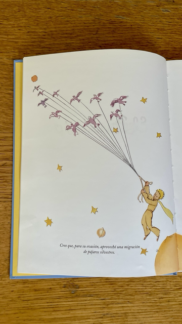 Portadilla del libro “El principito” de Antoine de Saint-Exupéry con una ilustración del autor. Aparece un niño agarrado a una serie de hilos tirados por pájaros. 