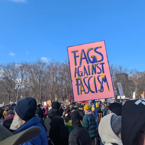Foto vom Winter-CSD in Berlin: ein Demoplakat mit der Aufschrift 

"Fags Against Fascism"