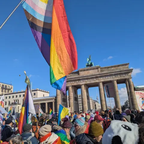 Foto vom Winter-CSD in Berlin: Regenbogenflaggen und die Demo vor dem Brandenburger Tor.