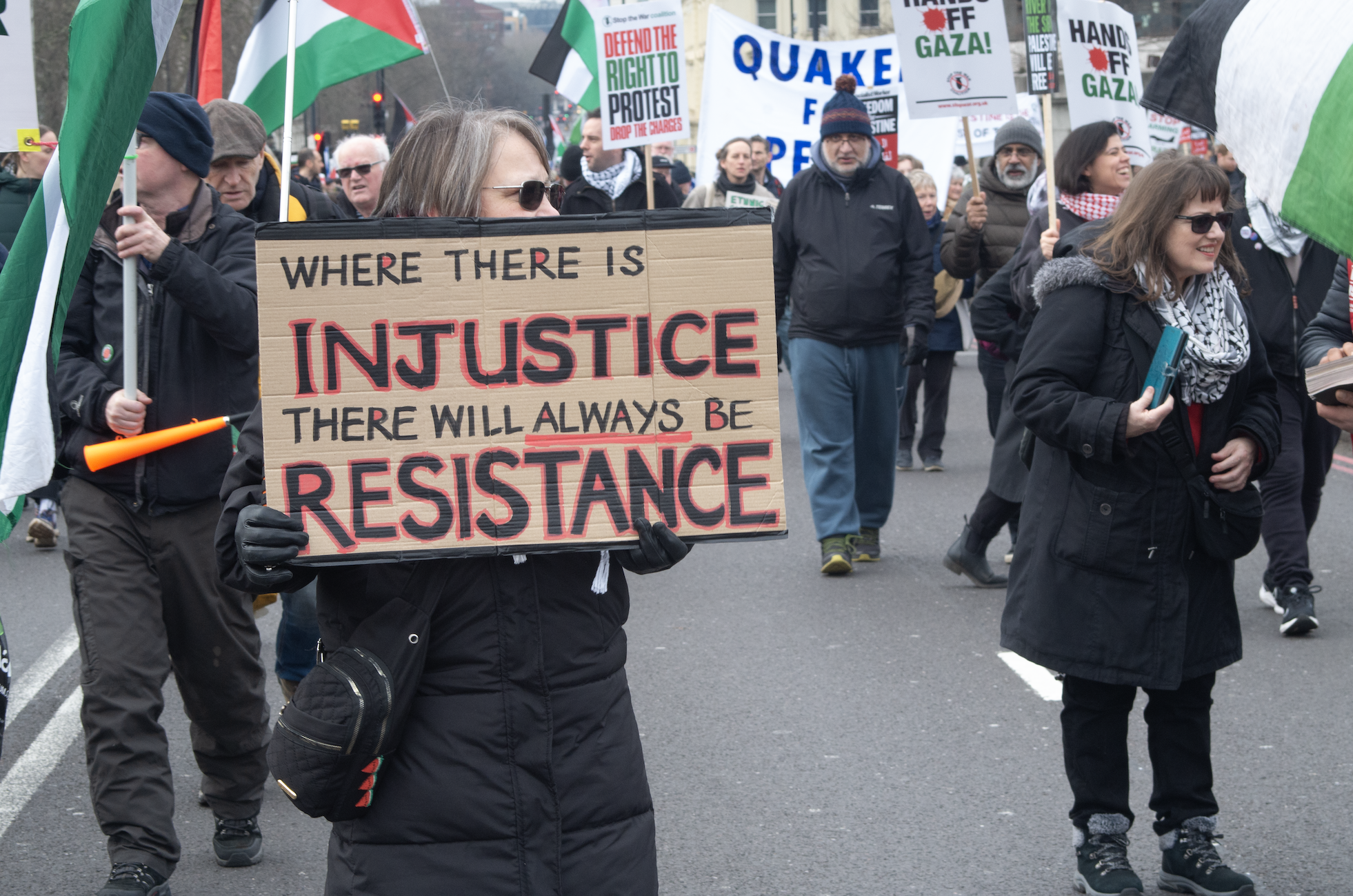 older woman carrying sign 'where there is injustice there will always be resistance'