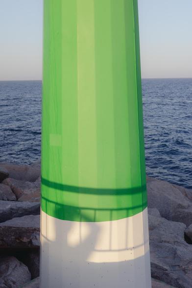 Photograph of a lighthouse in the port, in which a shadow of a person covering his eyes to look at the horizon is projected. The sea can be seen behind.

Fotografía de un faro en el puerto, en él se proyecta una sombra de una persona tapándose los ojos para mirar al horizonte. Detrás se ve el mar.