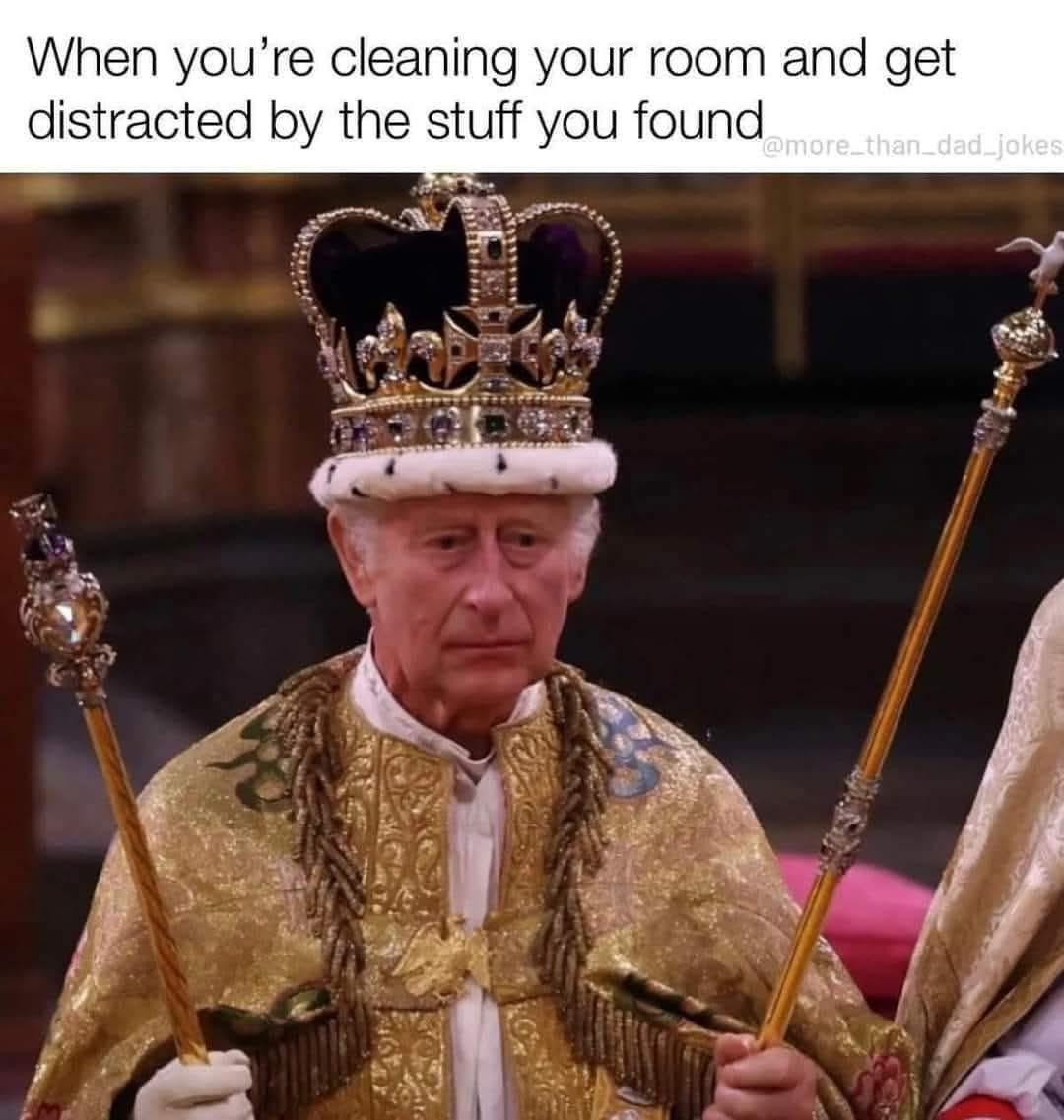 meme image shows King Charles III wearing a crown and a gold robe, holding two scepters. The text overlay reads, "When you're cleaning your room and get distracted by the stuff you found." The meme refers to the coronation regalia.