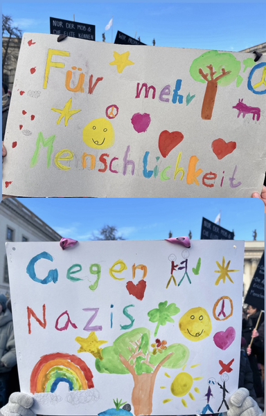 Zwei von Kindern bemalte bunte Plakate: für mehr Menschlichkeit gegen Nazis #wirsinddiebrandmauer #handinhand #b1602 #berlin 
