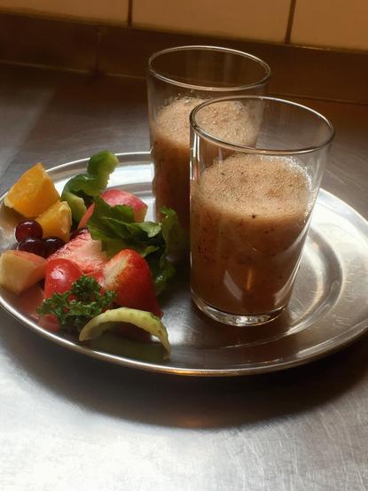 Auf einem silbernen Teller stehen zwei Gläser mit Smoothie und farbenfrohe, saftige Stückchen von Obst und Gemüse. Orangen, Weintrauben, Erdbeeren, rote und grüne Paprika, Sellerie, Apfel und Petersilie. Alle Zutaten sind heute gerettet worden. Die Smoothies und die Häppchen sind für alle Besucher von „Retten Teilen Helfen“. Guten Appetit.

In der Caféteria im Haus der Familie, Bei der Schilleroper 15, 22767 Hamburg finden regelmäßige eine Verteilungen, von geretteten Lebensmitteln an Gemeinschaftsküchen und Bedürftige statt.

Es können alle Besucher an einem Tisch sitzen und etwas Frühstücken. Beim gemeinsamen Zusammensein und Unterhalten über dies und das, verteilen wir untereinander freundschaftlich und gerecht alle gespendeten und geretteten Lebensmittel.

Wir beginnen mit den Gemeinschaftsküchen. Die bekommen stets zuerst. Hier wird das Obst und Gemüse an viele Menschen weiter gereicht. 

Danach schauen wir gemeinsam wie viele Besucher wir sind und wie viele Waren in unseren Kisten sind, um eine faire und gerechte Aufteilung zu ermitteln. 

Alle sind herzlich eingeladen, uns zu besuchen. Die verteilten Lebensmittel sind für alle gedacht, denen es finanziell besser gehen könnte. Rentner*innen, Bürgergeldempfänger*innen, Geflüchteten oder Geringverdiener*innen, die jeden Cent zweimal umdrehen müssen, wollen wir Unterstützung geben.