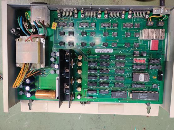 Gesamtansicht des Gerätes mit Trafo und Leiterplatte . Zu erkennen sind eine 7 Segment Anzeige ein Mikroprozessor , EPROM, Dip-Schalt und diverse ICs. Sowie 4 Relais.