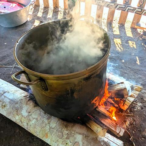 A large pot steaming over a fire.