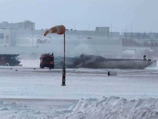 Far away view of the upside down aircraft. Snow present and winds. 